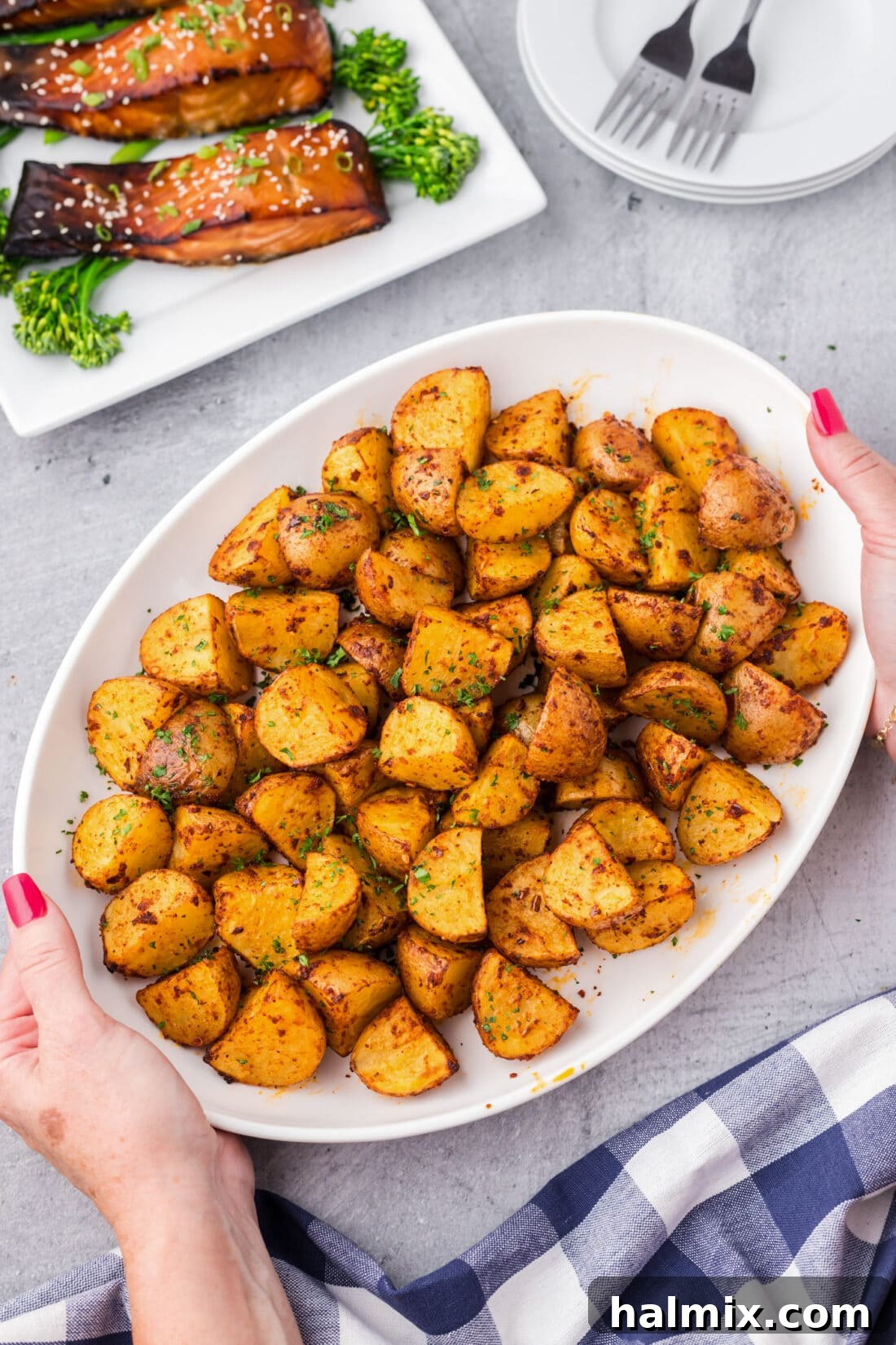 A vibrant platter of freshly cooked spicy potatoes, held by hands, showcasing their crispy edges and tantalizing spice coating.