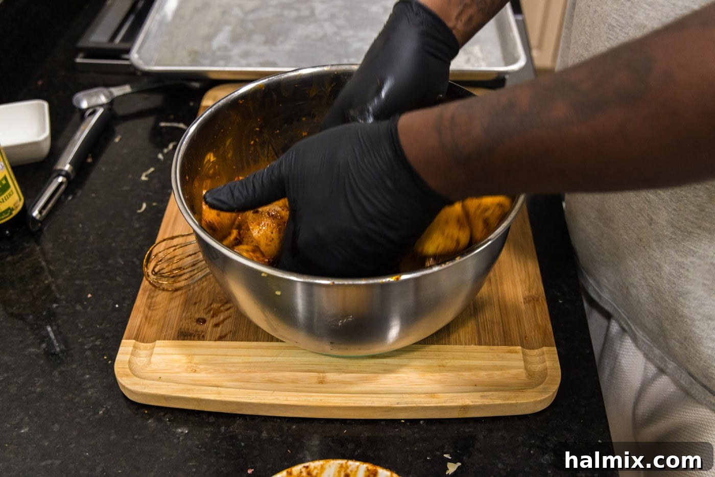Gloved hands expertly tossing quartered potatoes with the prepared spice blend in a mixing bowl.