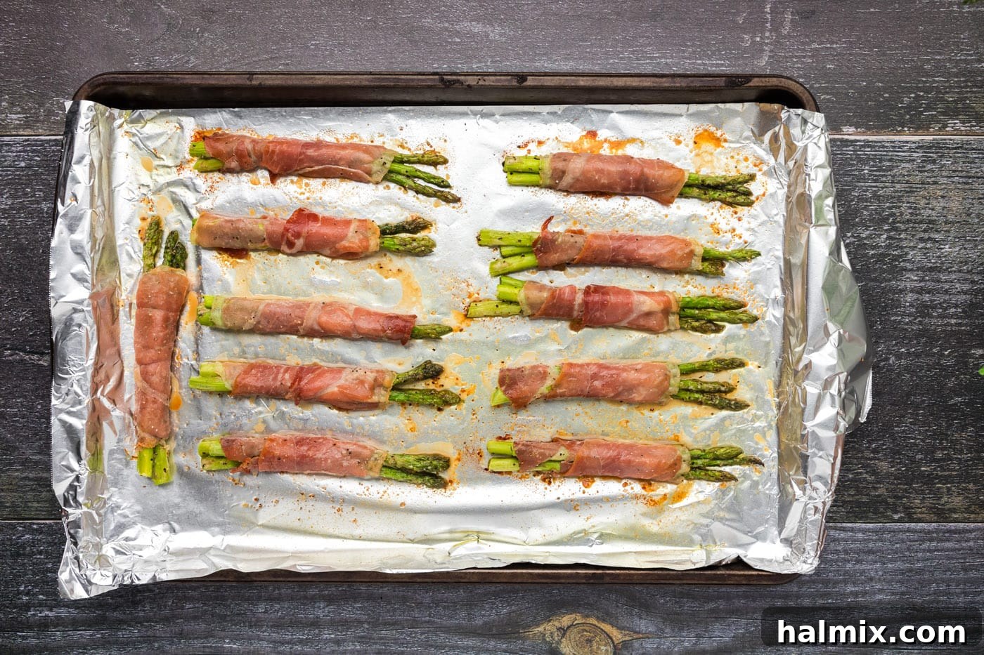 Prosciutto Asparagus Bundles 14 Crispy prosciutto wrapped asparagus bundles on a baking sheet, fresh out of the oven.