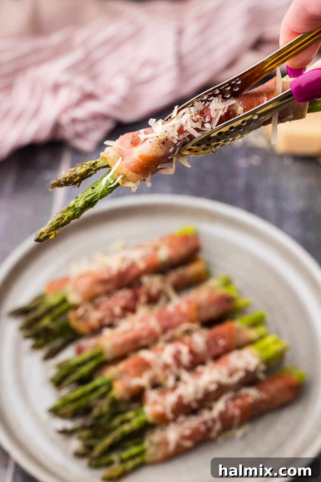 Prosciutto Asparagus Bundles 15 Kitchen tongs holding up a golden-brown Prosciutto Wrapped Asparagus bundle, ready to be served.