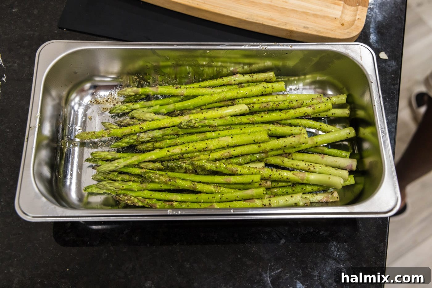 Prosciutto Asparagus Bundles 7 Seasoned asparagus spears resting in a baking tray, ready for wrapping.