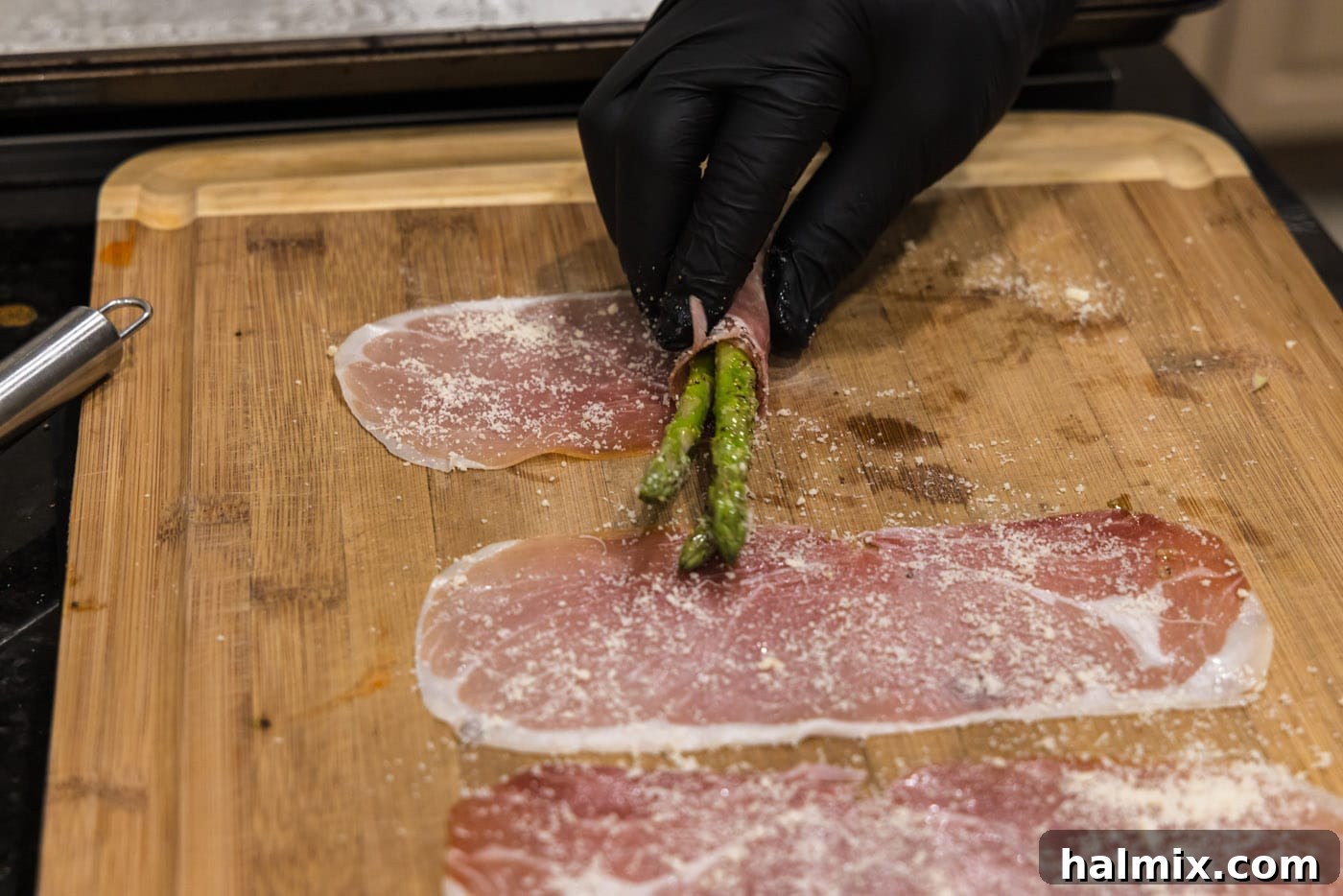 Prosciutto Asparagus Bundles 10 A close-up of the rolling process, showing how to wrap asparagus tightly in prosciutto.