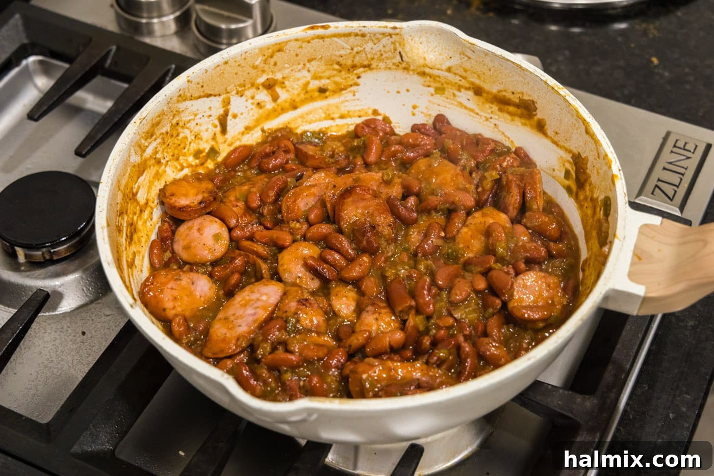 Bayou Red Beans and Rice Legacy 13 sliced andouille sausage blended into the creamy Cajun red beans in a skillet, ready for final heating