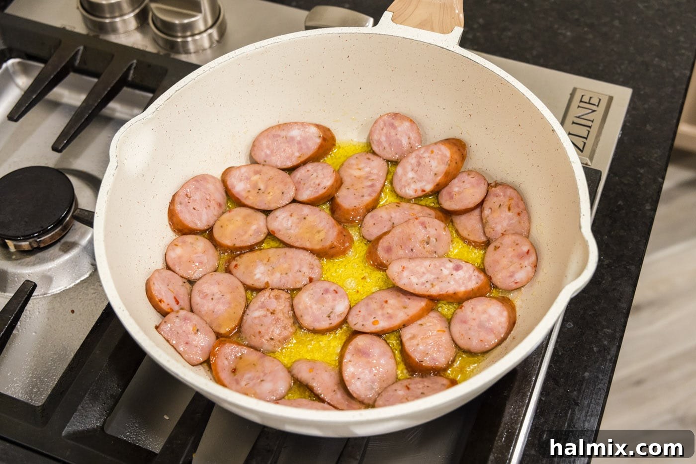 Bayou Red Beans and Rice Legacy 5 sliced andouille sausage sizzling in olive oil in a skillet, turning golden brown