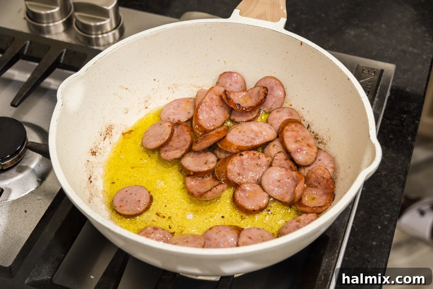 Bayou Red Beans and Rice Legacy 6 close-up view of andouille sausage cooking in a hot skillet, achieving a perfect sear