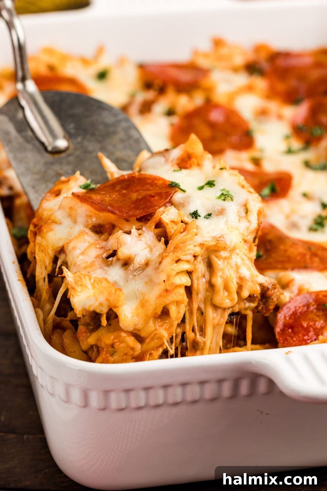 Cheesy Sausage Pepperoni Pizza Bake 3 Scoop of Sausage & Pepperoni Pizza Casserole being lifted out of the casserole dish
