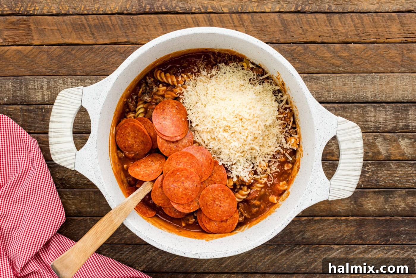 pepperoni and cheese added to pasta in a bowl