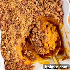 Spoonful of Sweet Potato Souffle resting in a baking dish of Sweet Potato Souffle