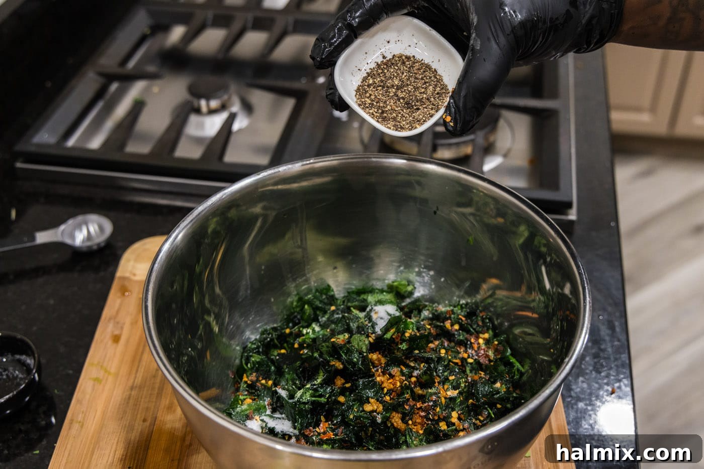 Seasoning crispy fried spinach and garlic with freshly ground black pepper for enhanced flavor