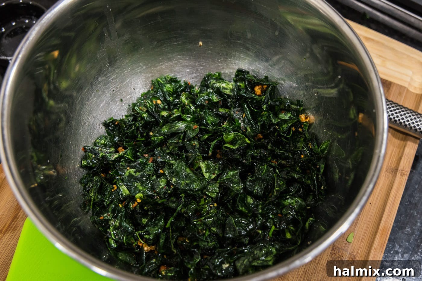 A large bowl of seasoned, tossed crispy fried spinach and garlic, ready to be served and enjoyed