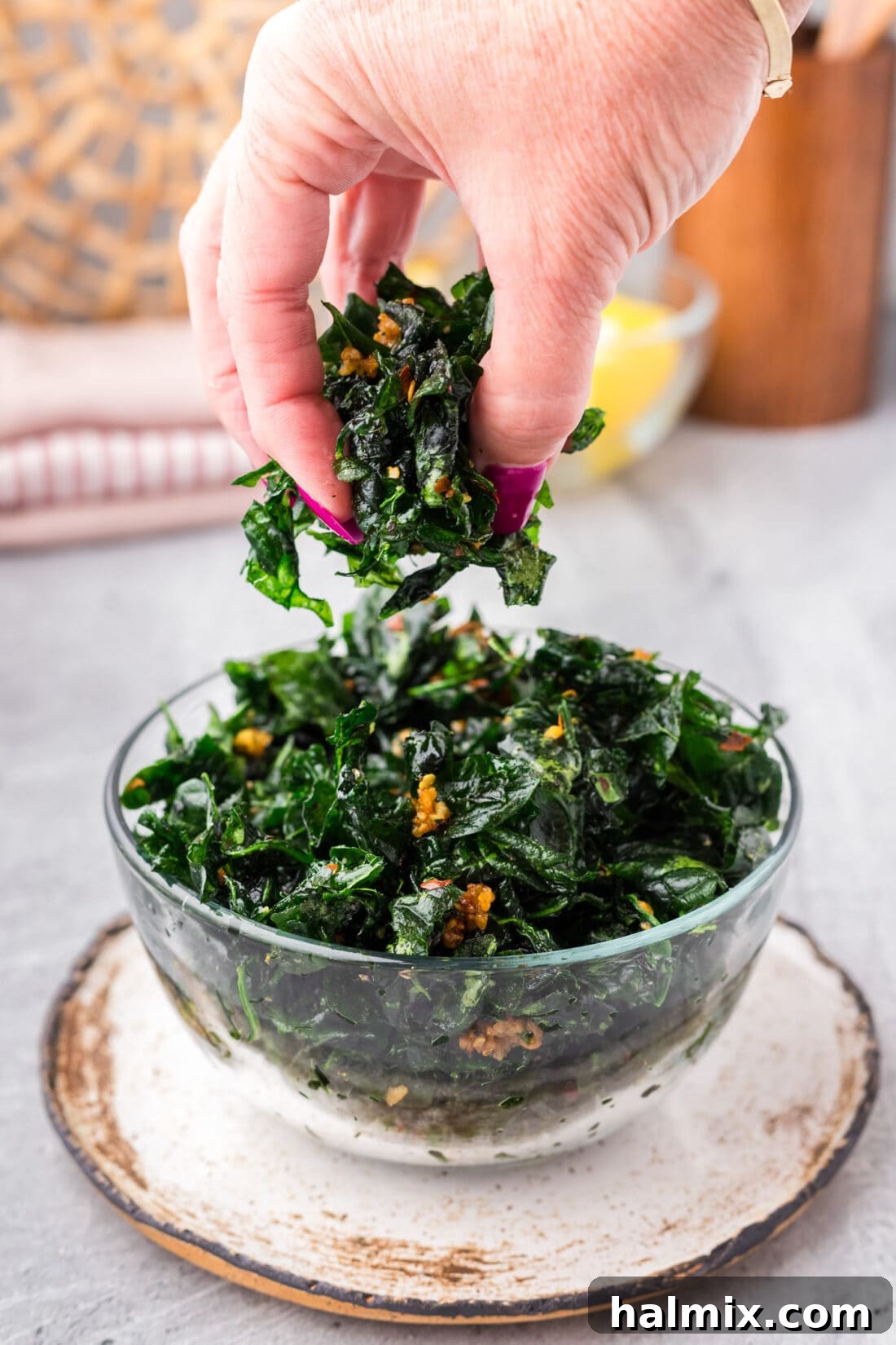 A hand reaching into a bowl of golden-brown Fried Spinach, emphasizing its crispy texture and inviting presentation