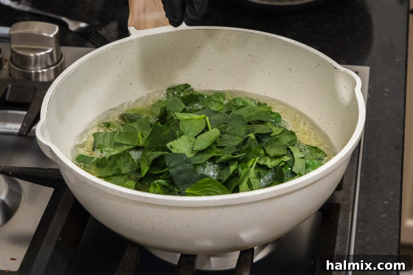 Fresh spinach leaves carefully lowered into shimmering hot oil in a skillet, beginning to crisp