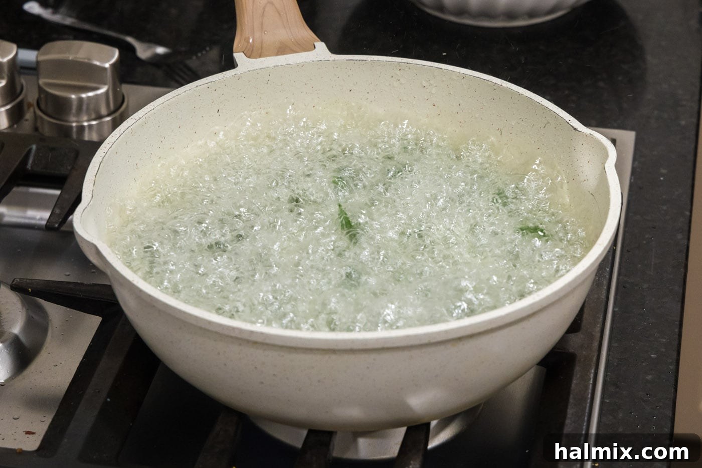 Spinach actively frying and bubbling in the hot oil, transforming into a crispy texture and darkening in color