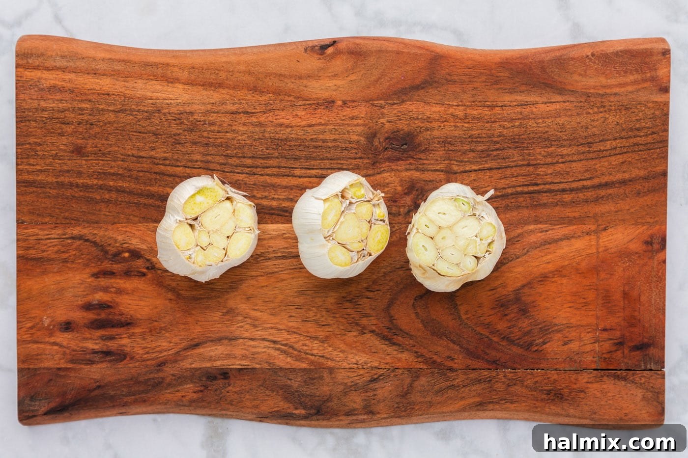 Close-up of garlic bulbs with their tops neatly sliced off, revealing the raw cloves inside, ready for olive oil.
