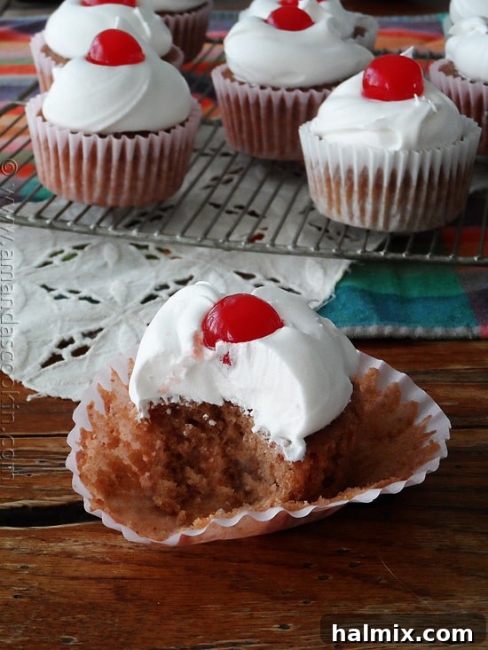 A close up photo of a half eaten cherry cupcake.