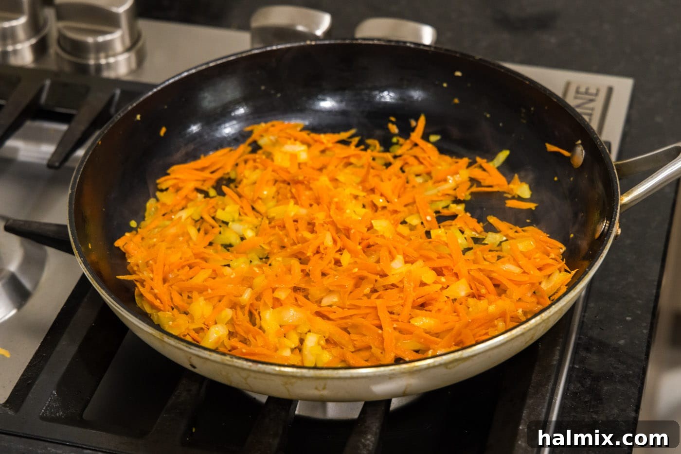 cooking garlic, onion, and shredded carrots in a skillet