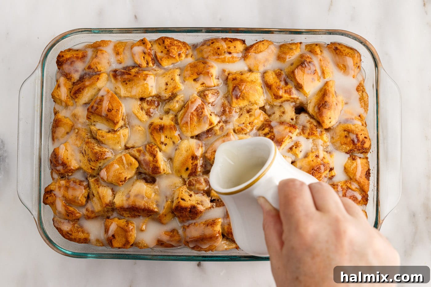 pouring icing over cinnamon roll casserole