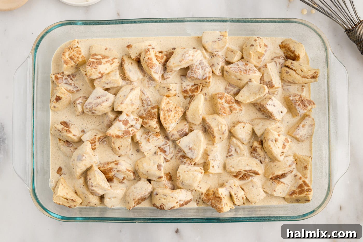 cream mixture poured over chopped cinnamon rolls in a baking dish