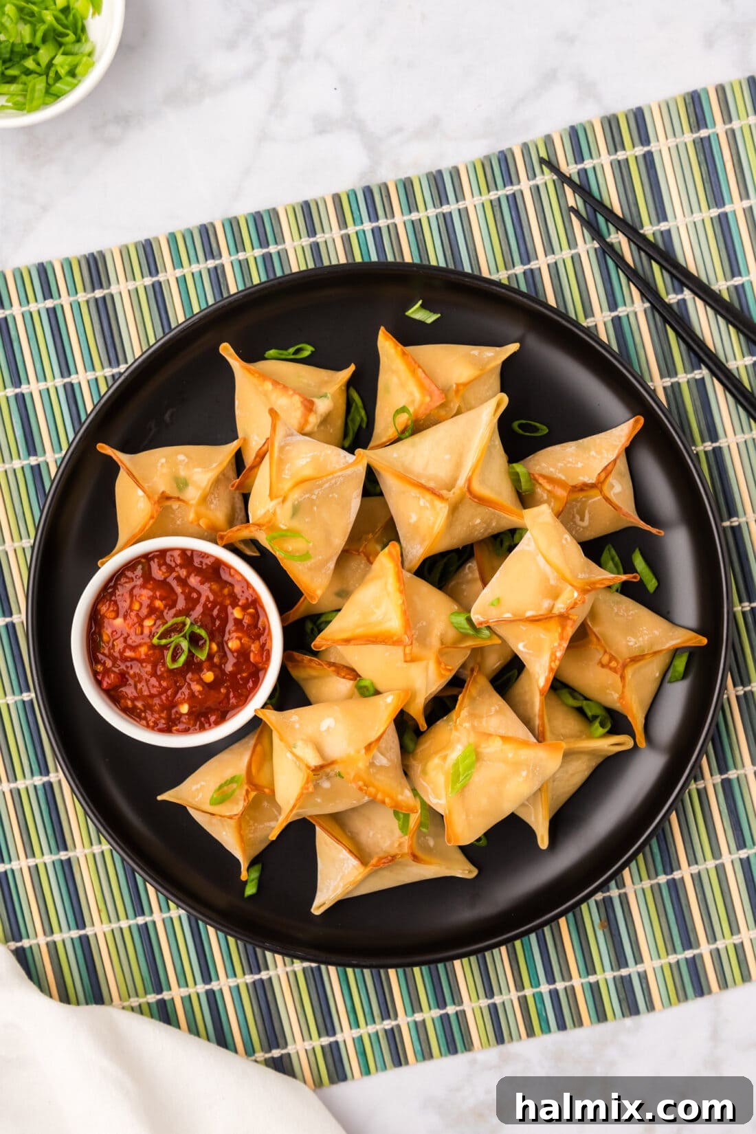 Overhead photo of a plate of perfectly baked Crab Rangoons, garnished and ready to eat.