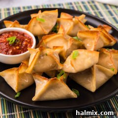 Close up photo of Crab Rangoons on a plate with dipping sauce