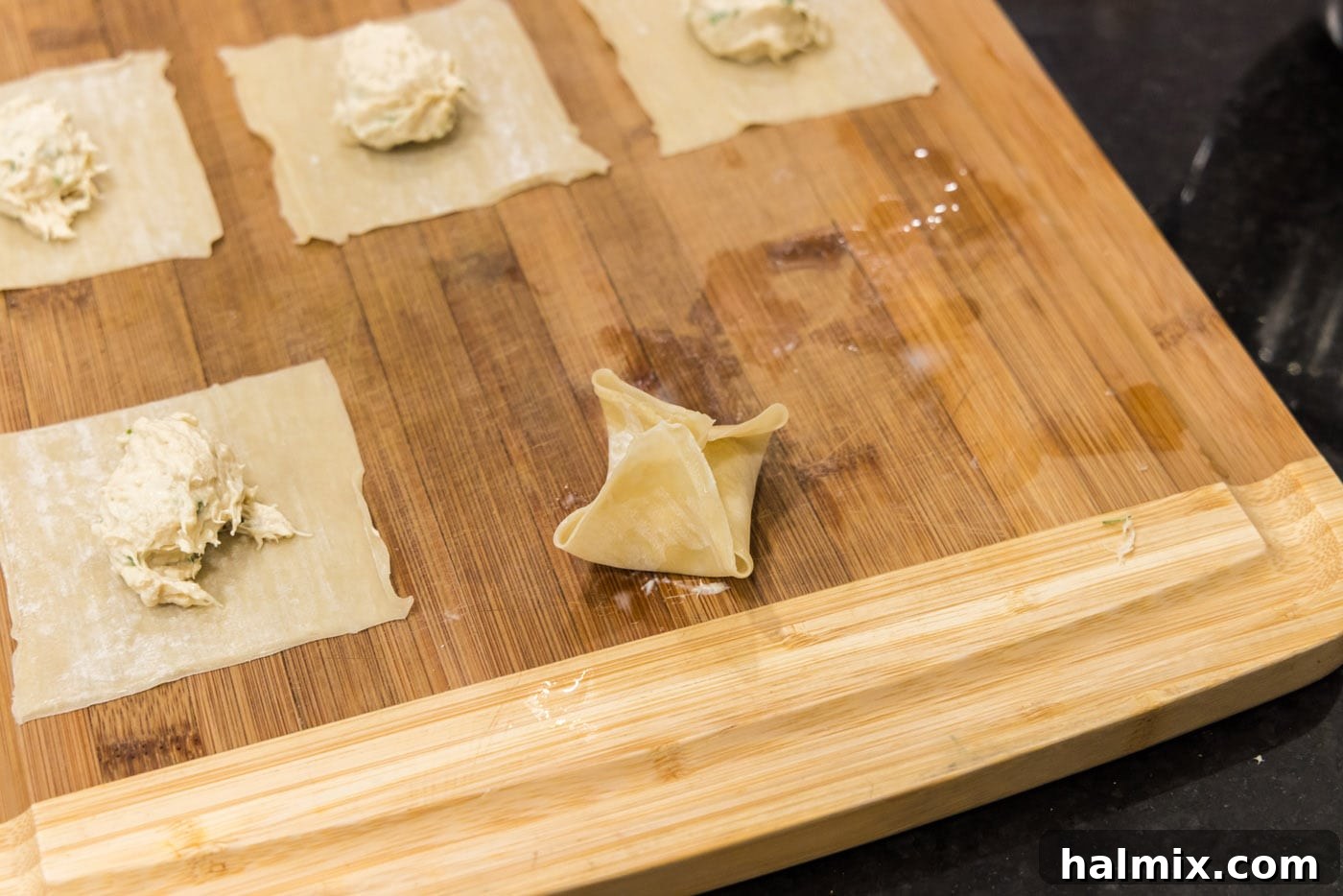 A fully folded crab rangoon, sealed at the top in a purse shape.