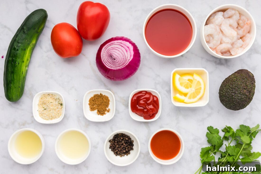 An overhead shot of various fresh ingredients for Mexican Shrimp Cocktail laid out on a clean surface, including shrimp, whole tomatoes, cucumbers, onions, cilantro, and bottles of sauces