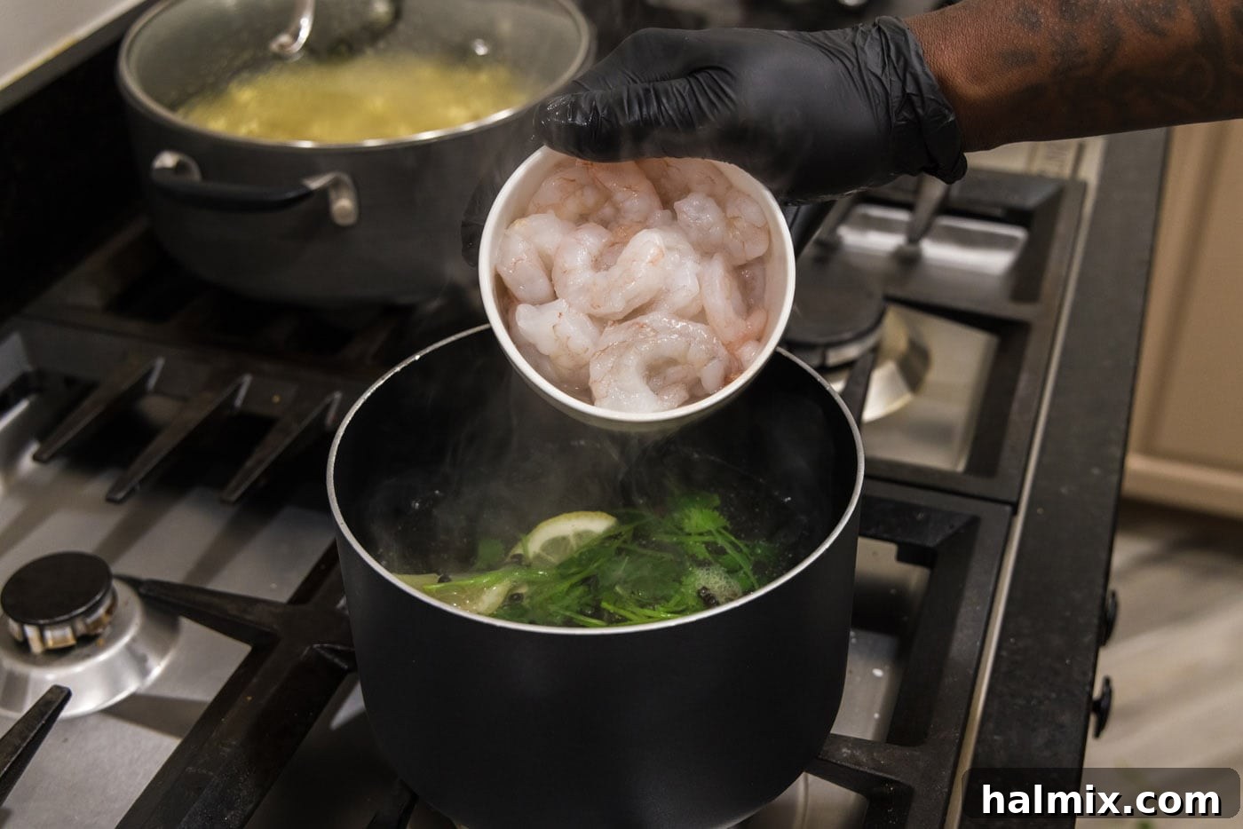 Raw shrimp being carefully placed into a pot of hot, infused water with cilantro and lemon