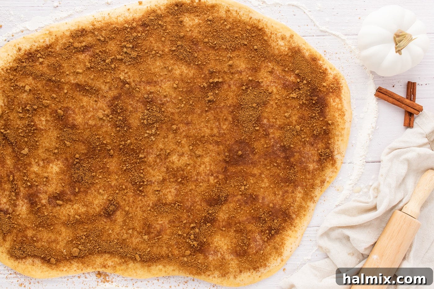 A generous layer of cinnamon, nutmeg, and brown sugar mixture spread over buttered cinnamon roll dough