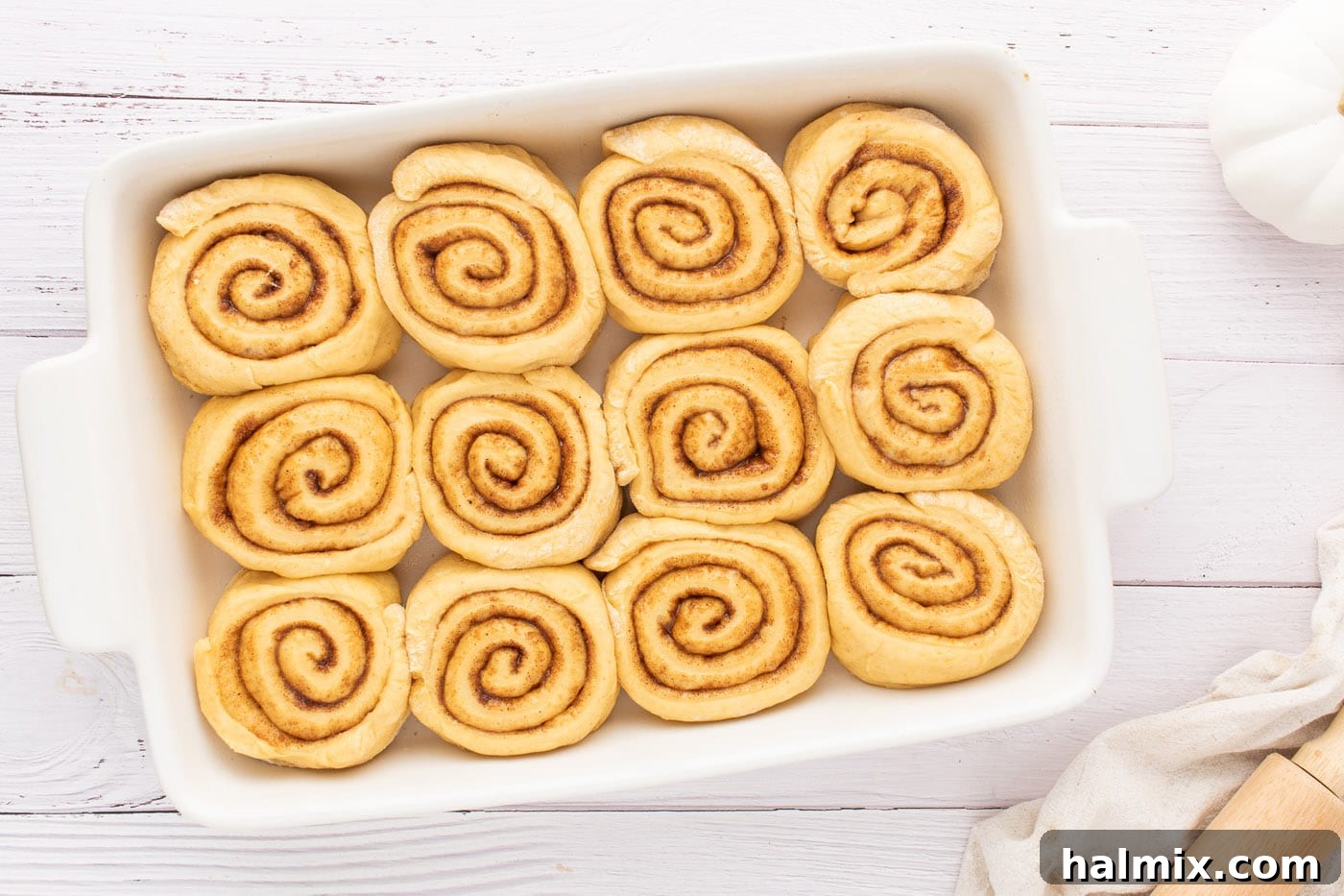 Precisely sliced cinnamon rolls arranged neatly in a baking pan