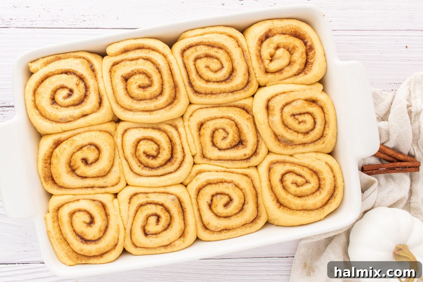Risen cinnamon roll dough filling a baking pan, ready for the oven