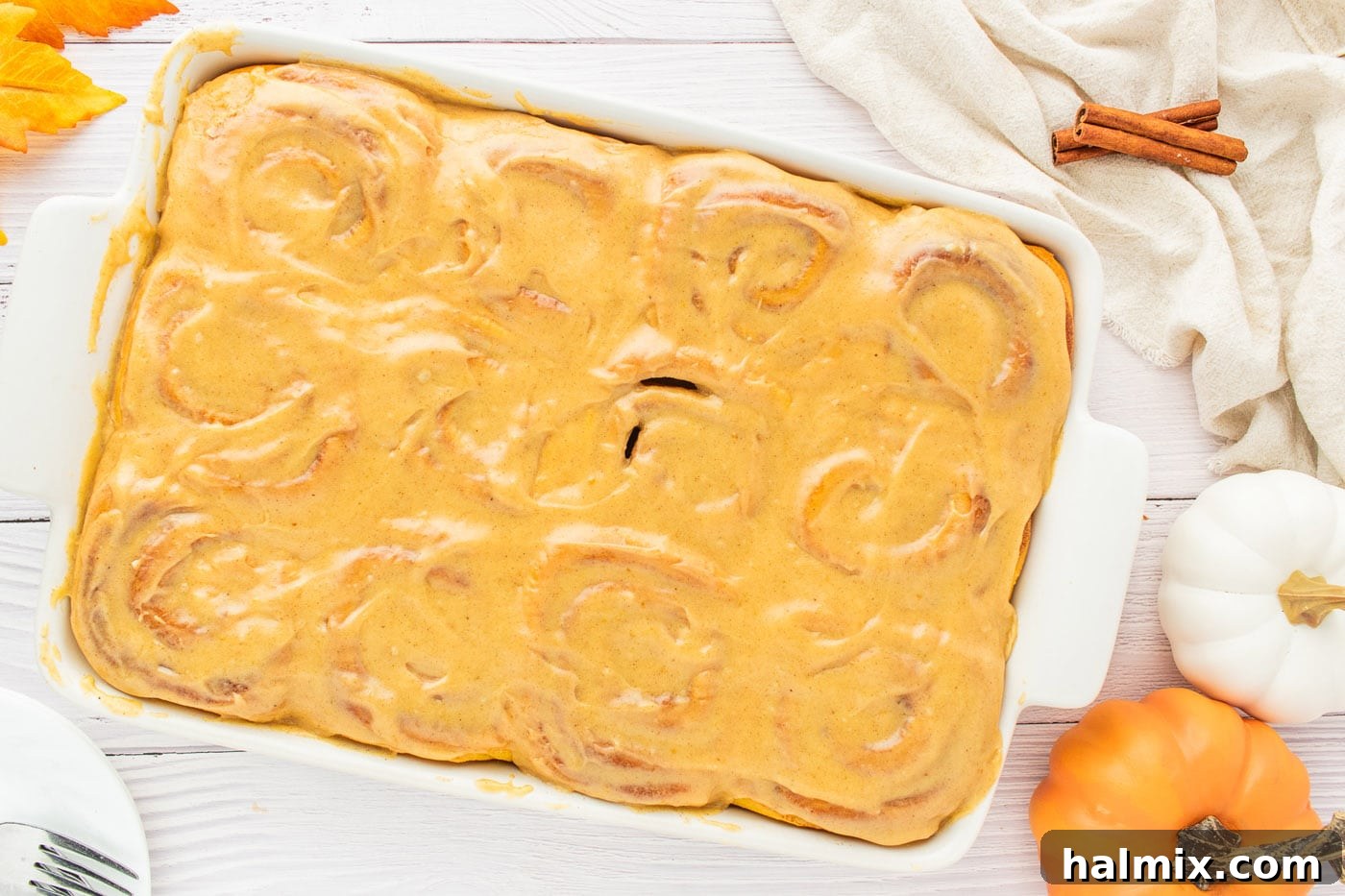 A pan of delicious pumpkin cinnamon rolls generously topped with rich pumpkin cream cheese frosting