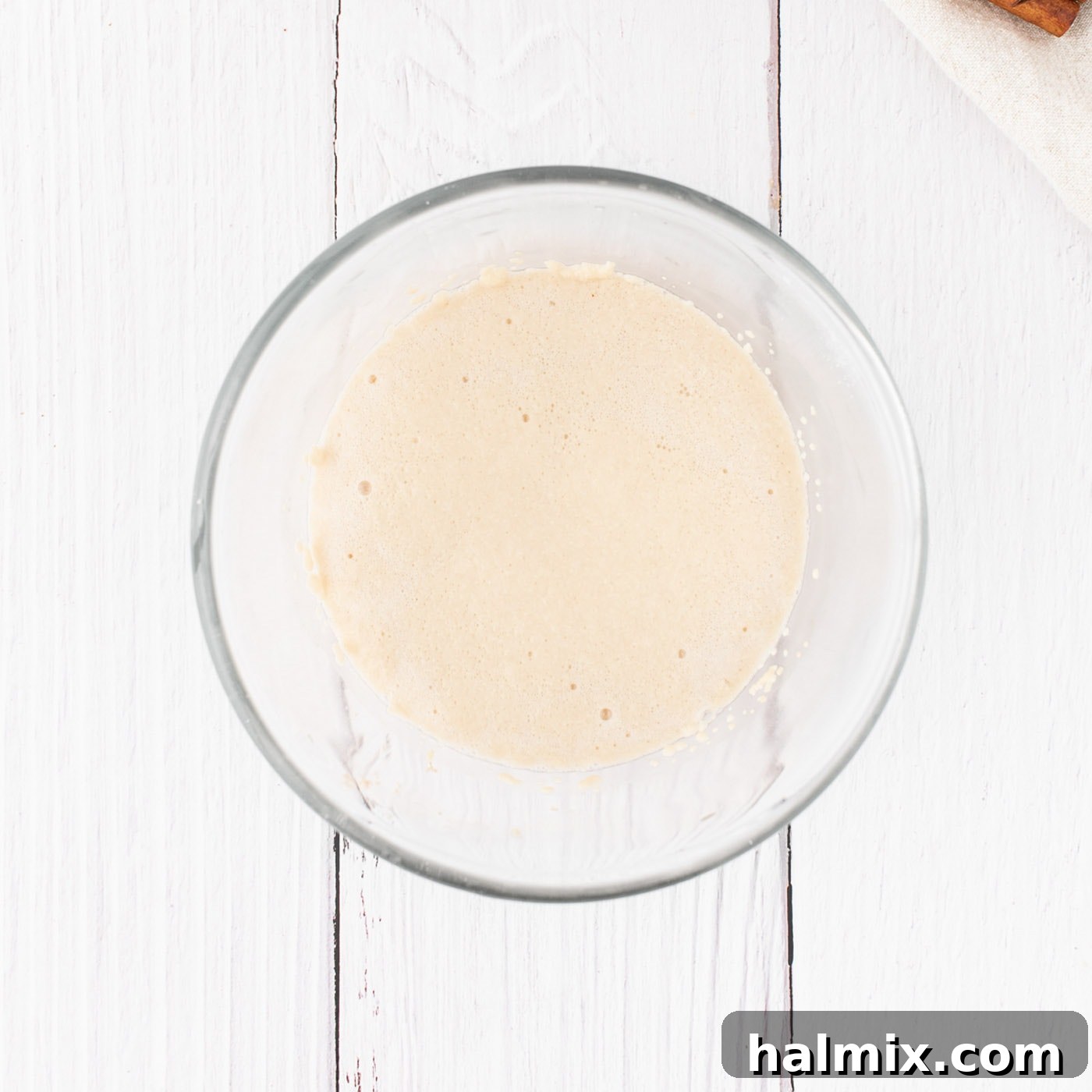 Active dry yeast, sugar, and warm water in a small bowl, showing foam forming on top