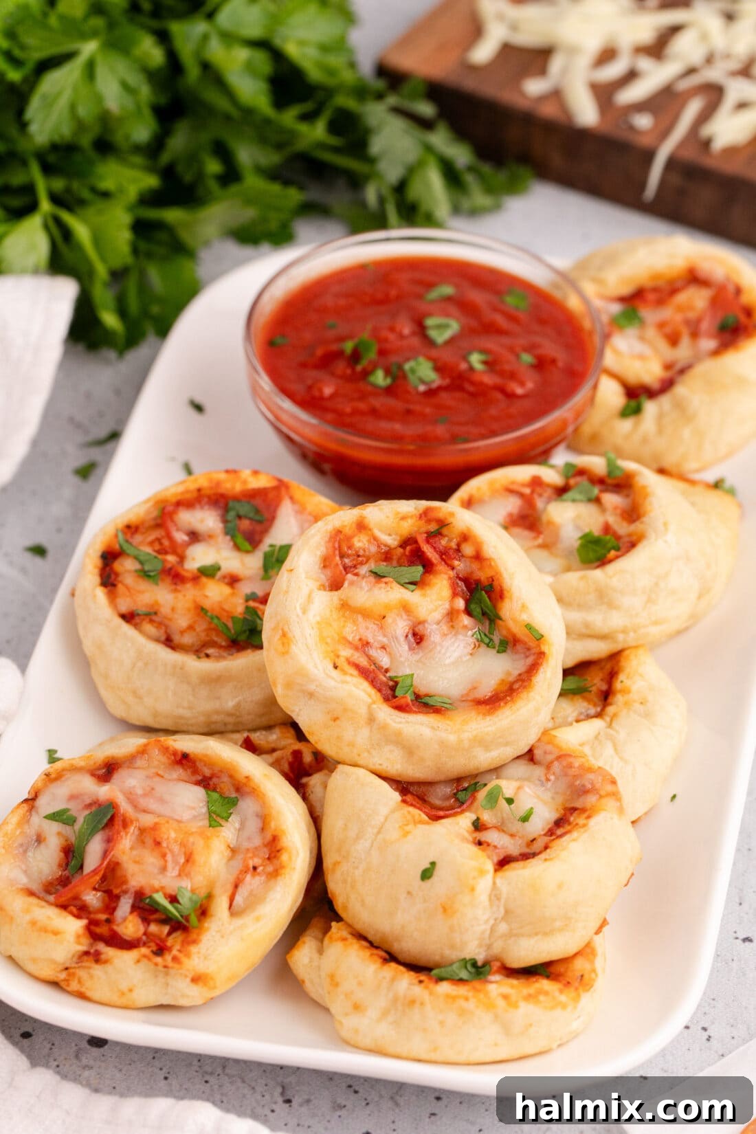 Pizza Pinwheels on a platter with pizza sauce in a bowl
