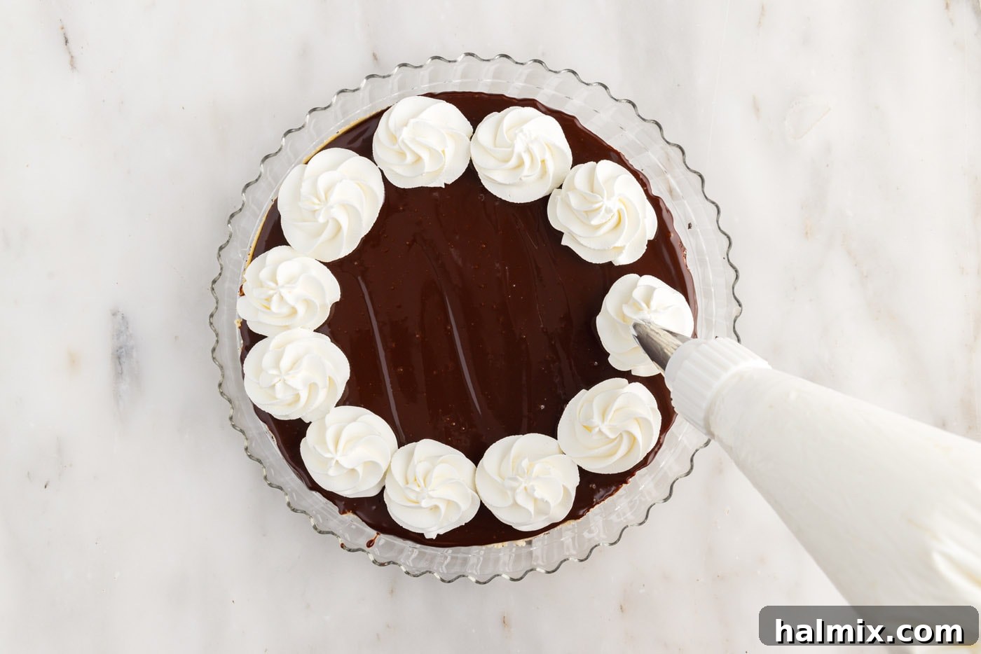 piping whipped cream onto cheesecake