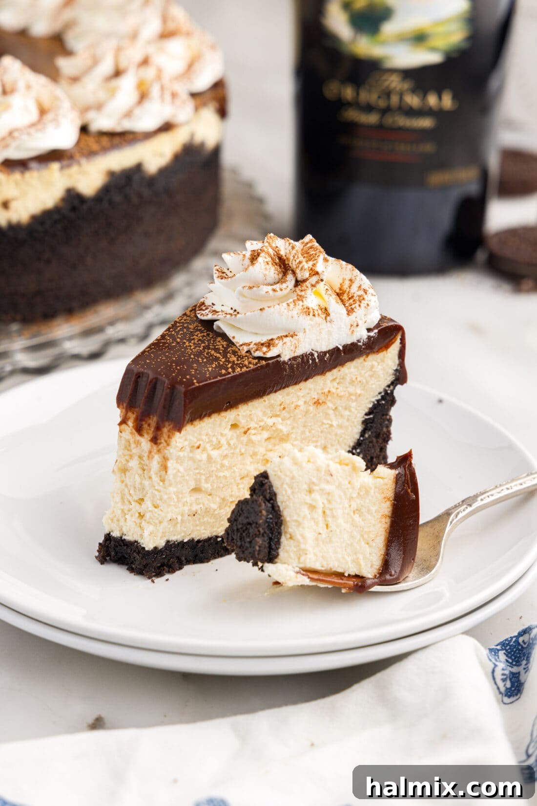 Slice of Baileys Cheesecake on a plate with a bite removed, showing the layers.