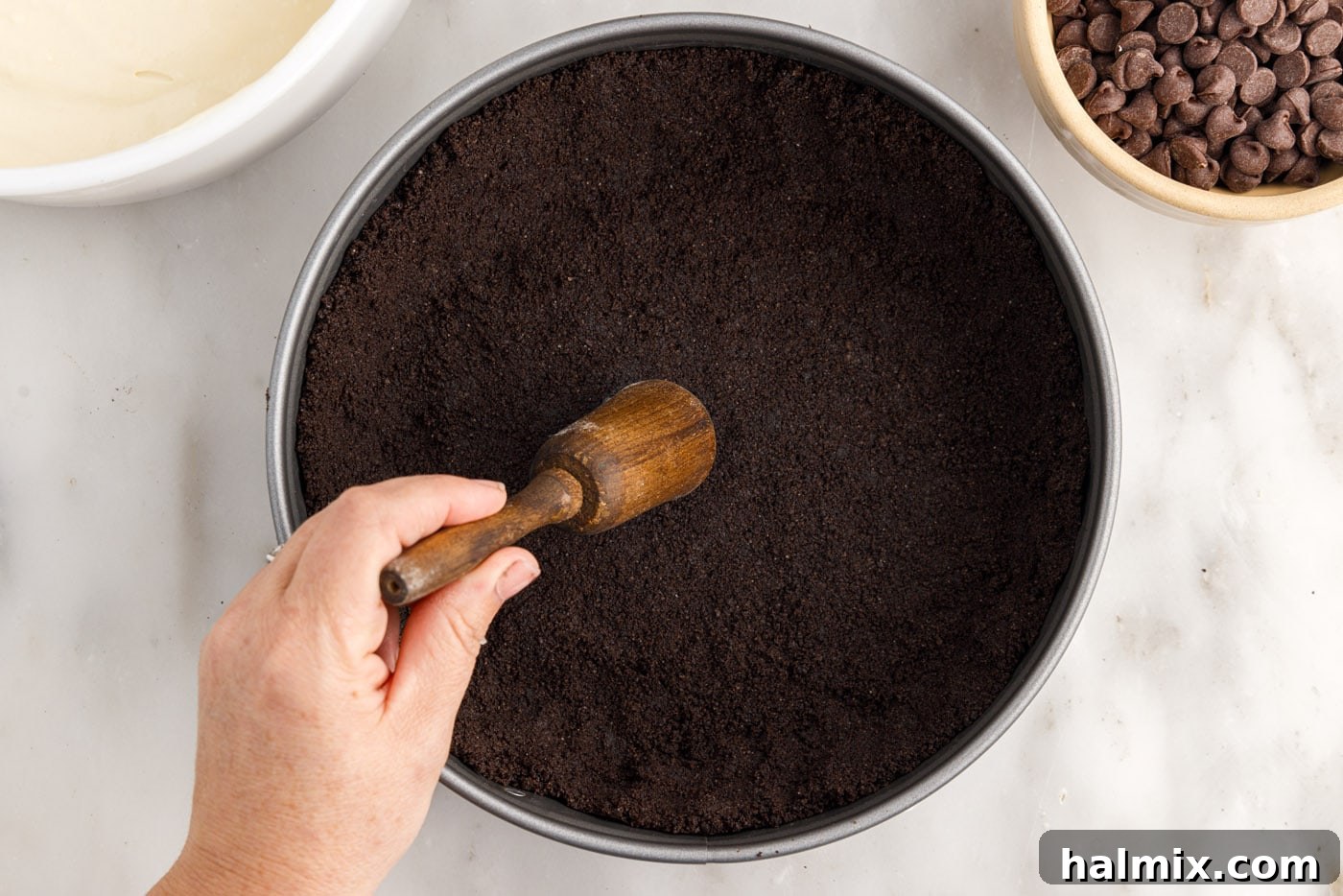 flattening oreo crumbs into a springform pan