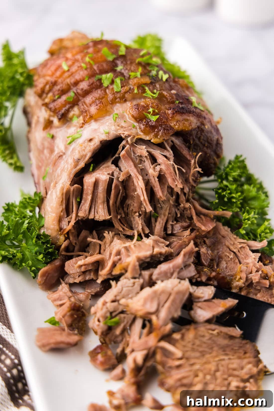 Roasted Leg of Lamb 2 Close up photo of a perfectly roasted Leg of Lamb on a platter, showcasing its golden-brown exterior and juicy texture.