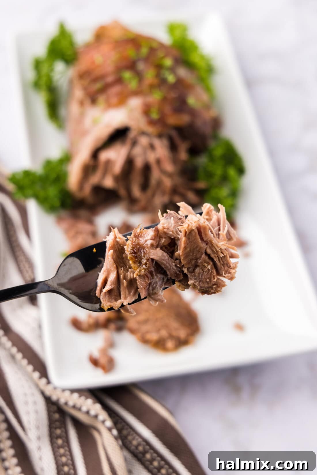 Roasted Leg of Lamb 3 Pieces of Leg of Lamb on a fork, demonstrating its pull-apart tenderness and succulence.
