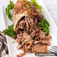 Close up photo of Leg of Lamb on a platter half shredded, perfect for a recipe card thumbnail.