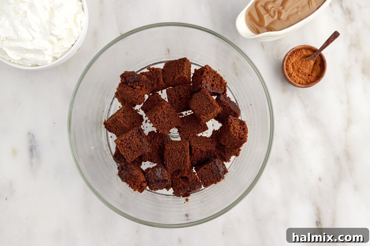 Cubed gingerbread cake pieces arranged in the bottom of a trifle bowl