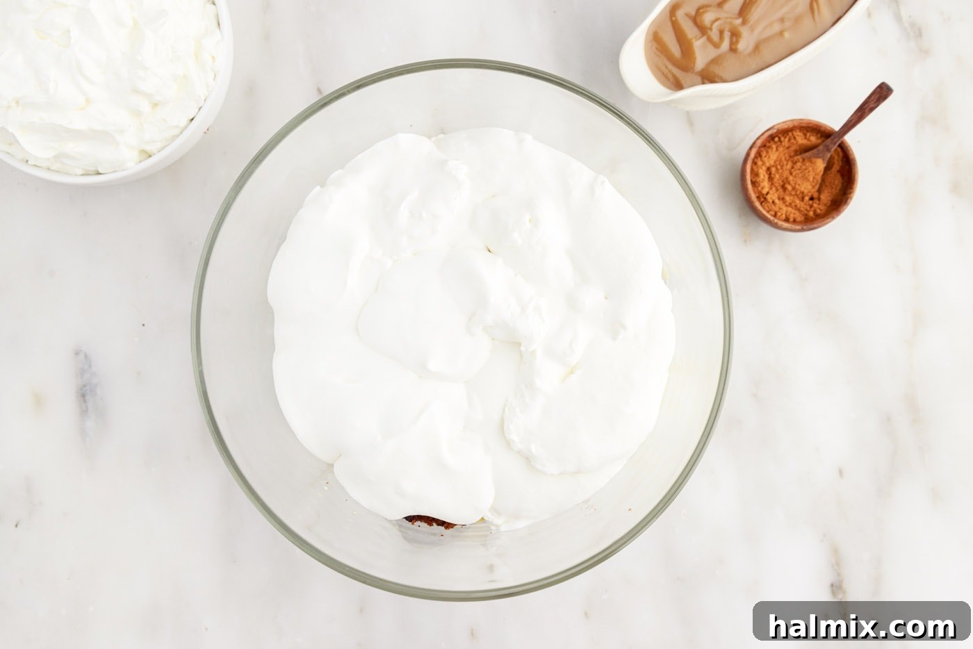 A layer of whipped cream spread evenly over the pudding and gingerbread cake