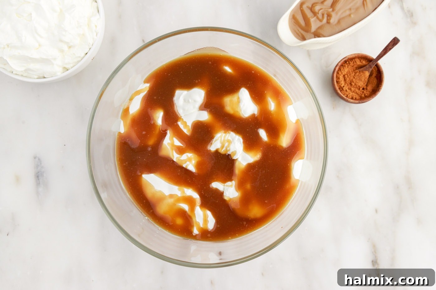 Caramel sauce being drizzled over the whipped cream layer in the trifle