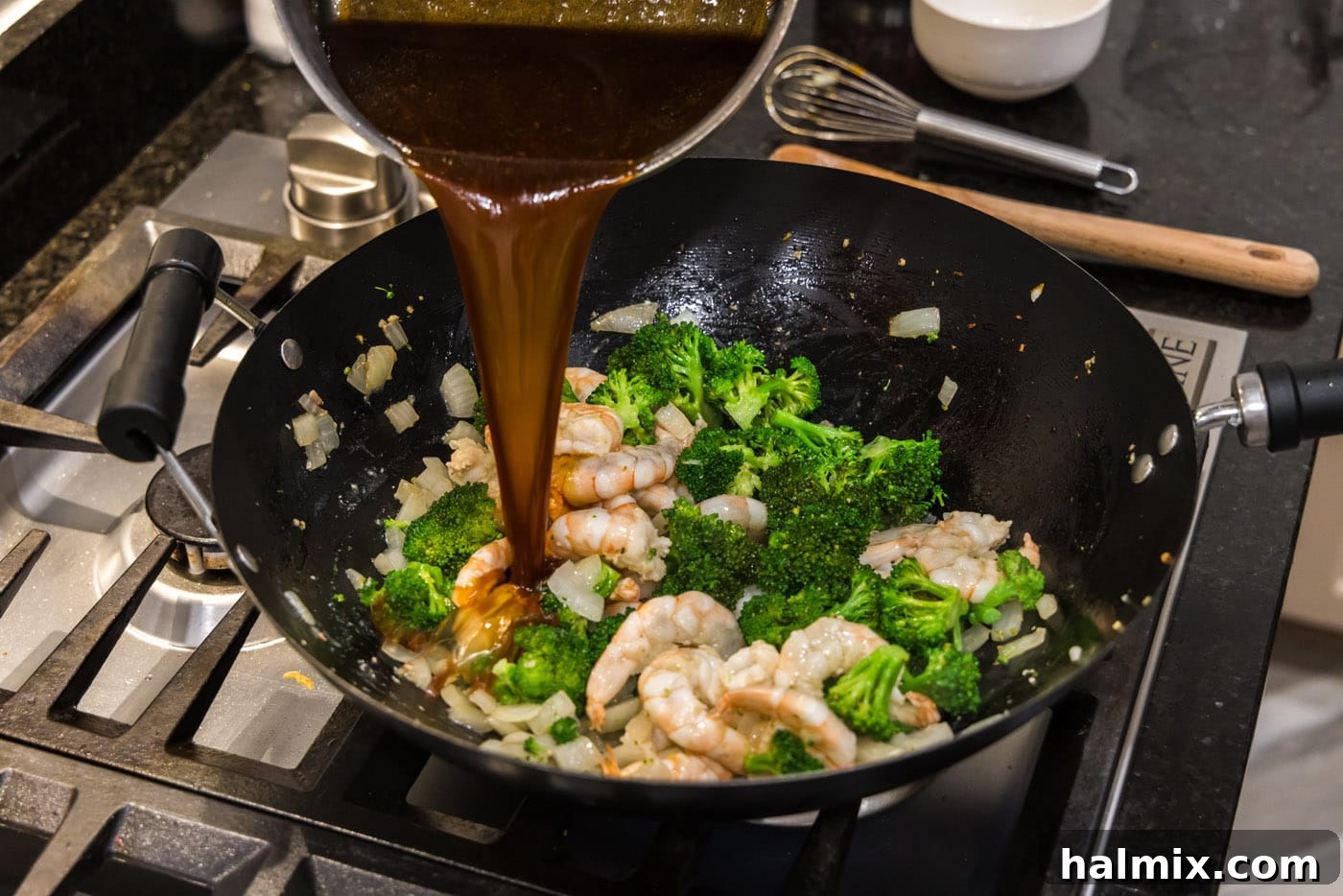 pouring sauce over shrimp and broccoli in a wok