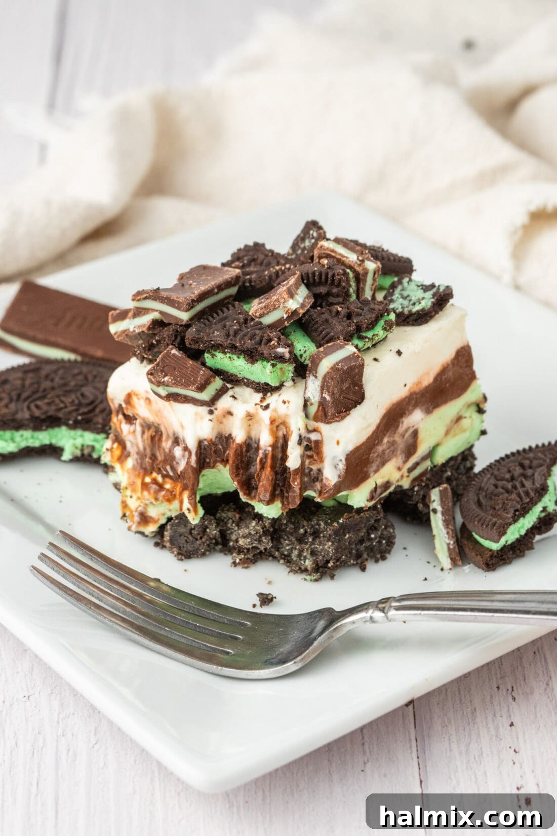 A slice of Mint Chocolate Dream Bar with a bite taken out, resting on a white plate next to a fork.