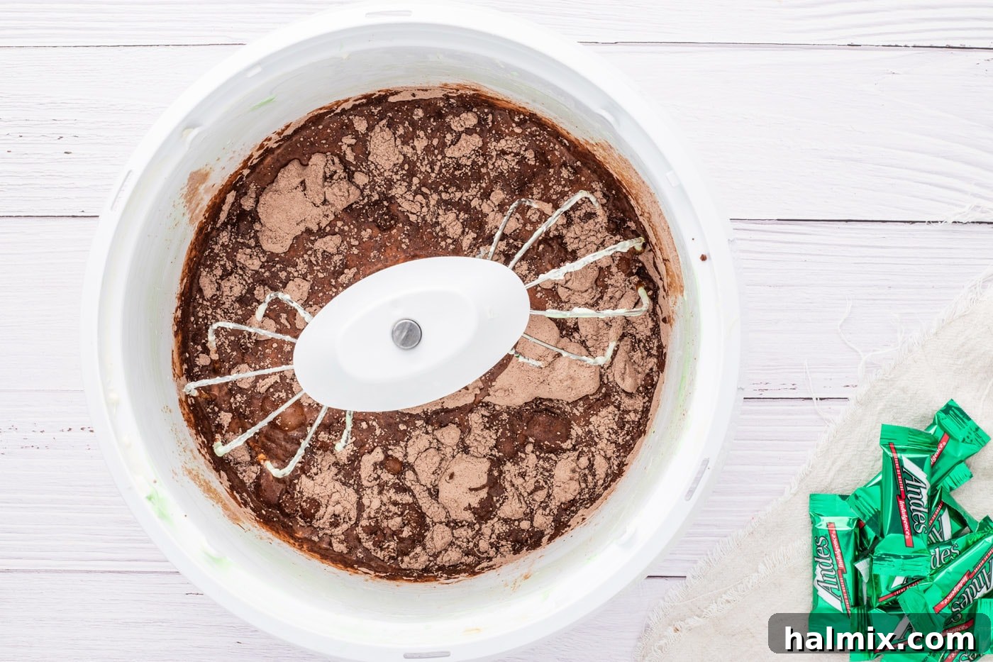 Chocolate fudge pudding mix being combined with milk in a mixer bowl.