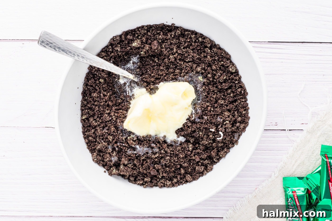 Oreo cookie crumbs mixed with melted butter in a bowl.