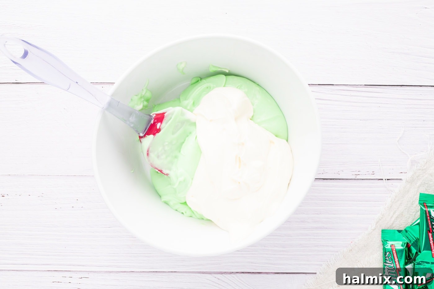 Folding thickened whipped cream into the peppermint cream cheese mixture.