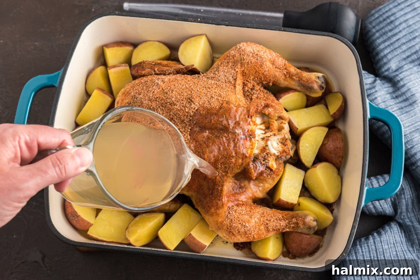 Irresistibly Sticky Slow Roasted Chicken 8 pouring chicken stock over whole roasted chicken in pan with potatoes