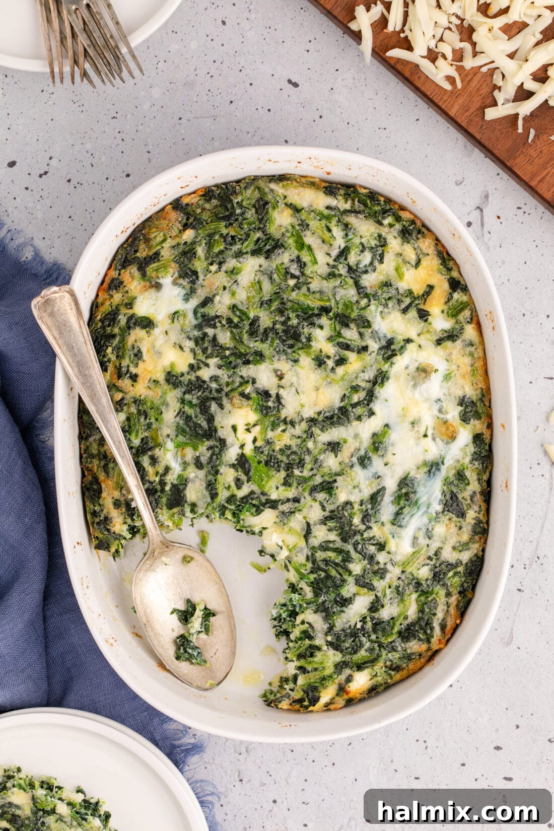 Overhead photo of a spoon resting in a Spinach Souffle, showcasing its rich texture and golden-brown crust.