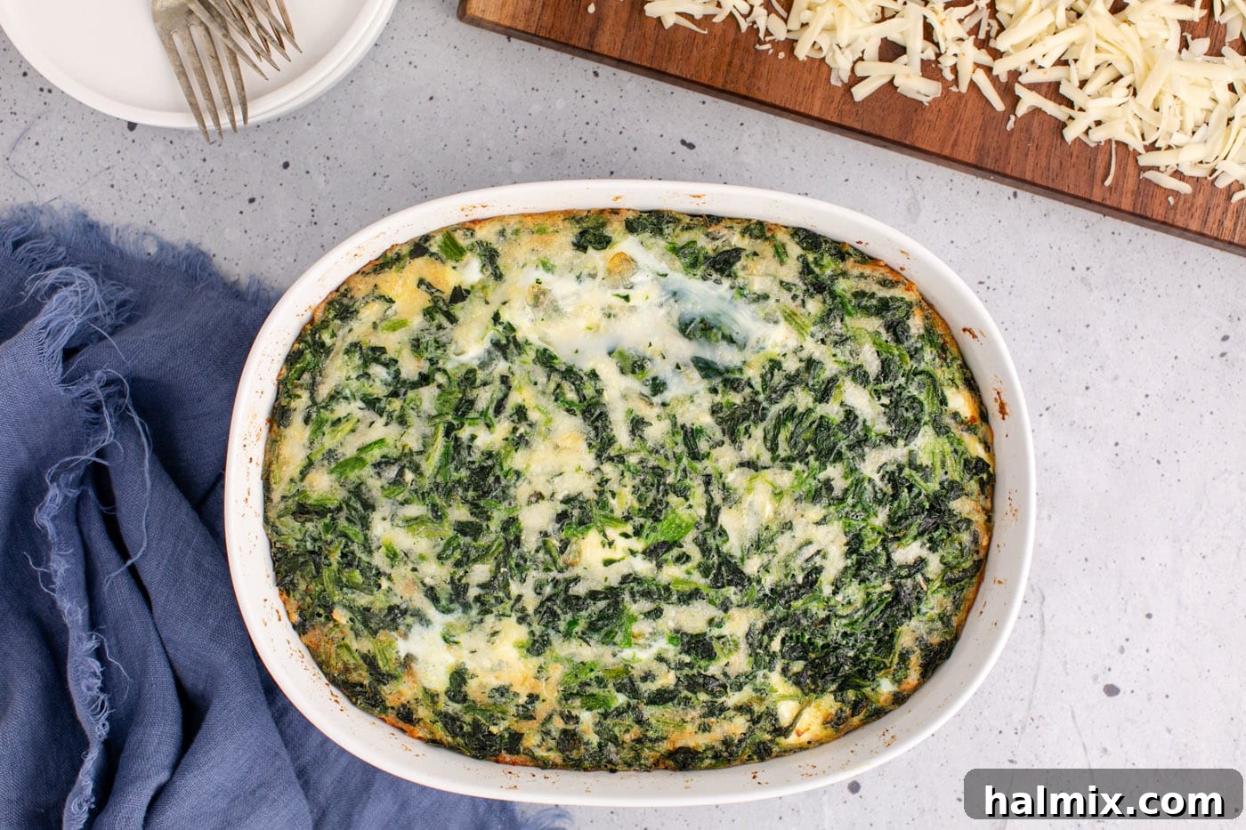 A perfectly baked spinach souffle in a casserole dish, showing golden-brown edges and a puffed center, just out of the oven.